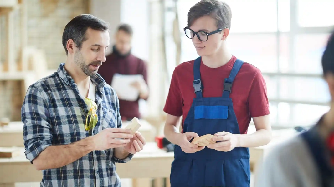 Vocational trainer teaching a young apprentice during a carpentry session – Apply for Ausbildung in Germany From Abroad.