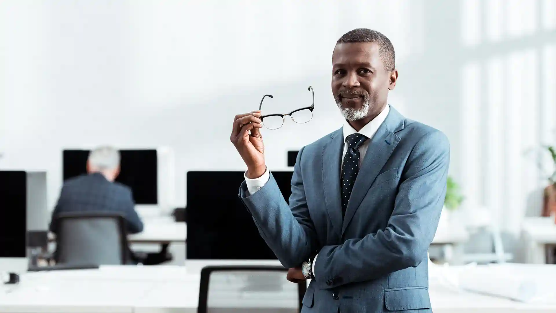 Confident professional man in a business suit in modern office setting, representing what is a good salary in Germany for experienced professionals.