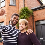 Excited couple standing outside their new home, symbolizing success in the journey of How to Buy Property in Germany as a Foreigner