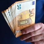 A person holding multiple €50 euro banknotes, symbolizing income and financial planning when evaluating what is a good salary in Berlin