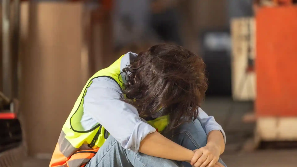 factory worker feels burnout sitting on the ground regretfully of doing Undeclared Work in Germany