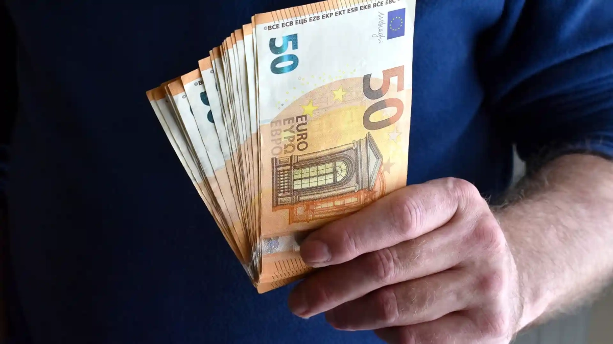 A person holding multiple €50 euro banknotes, symbolizing income and financial planning when evaluating what is a good salary in Berlin