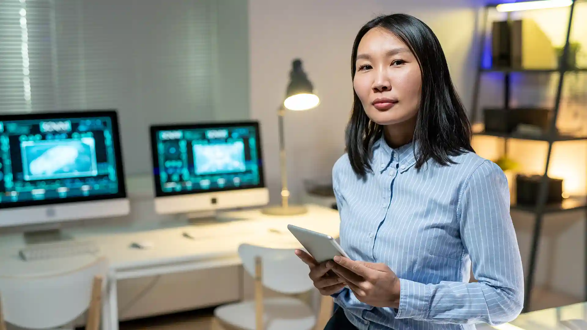 Asian woman holding a tablet in a tech office, symbolizing how to find tech jobs in Germany as an international professional.
