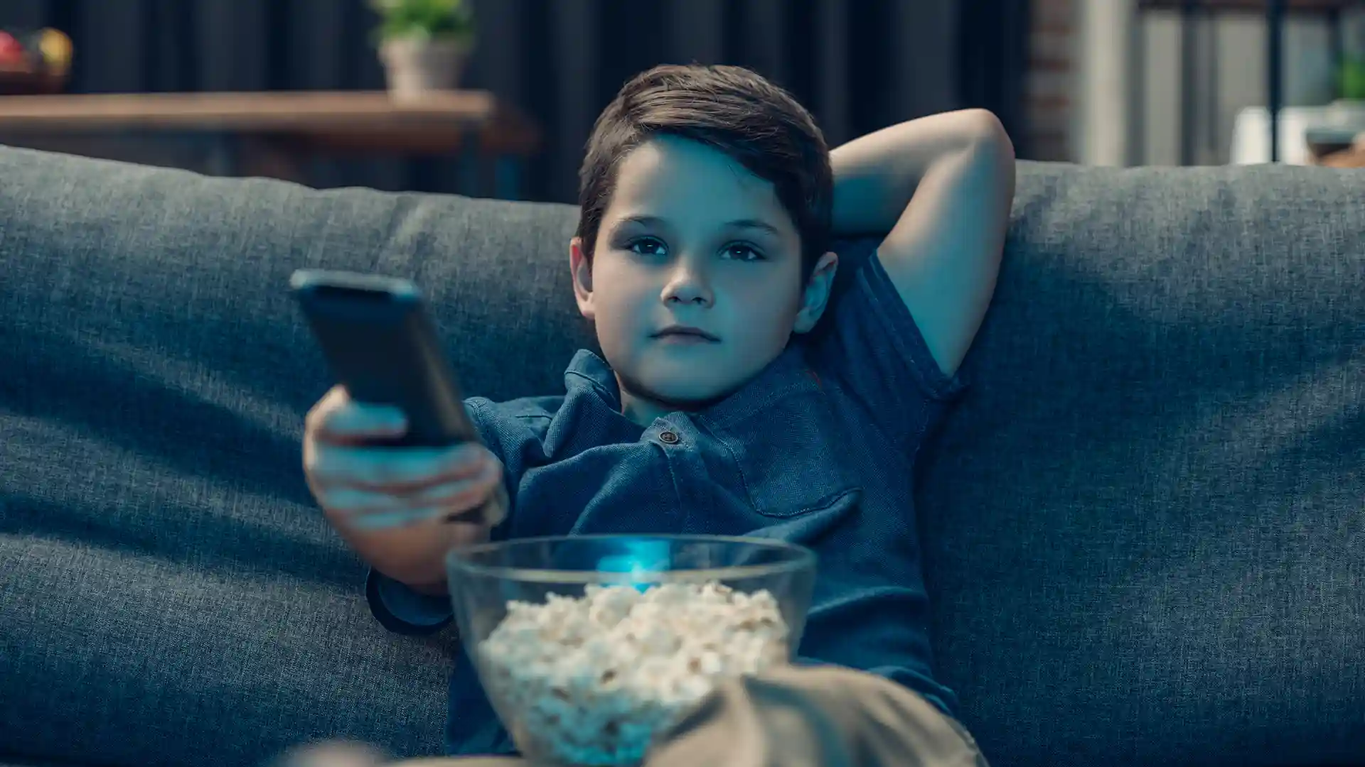 Young child watching TV and eating popcorn – symbolic of unsupervised internet use and risk of illegal downloads by minors in Germany