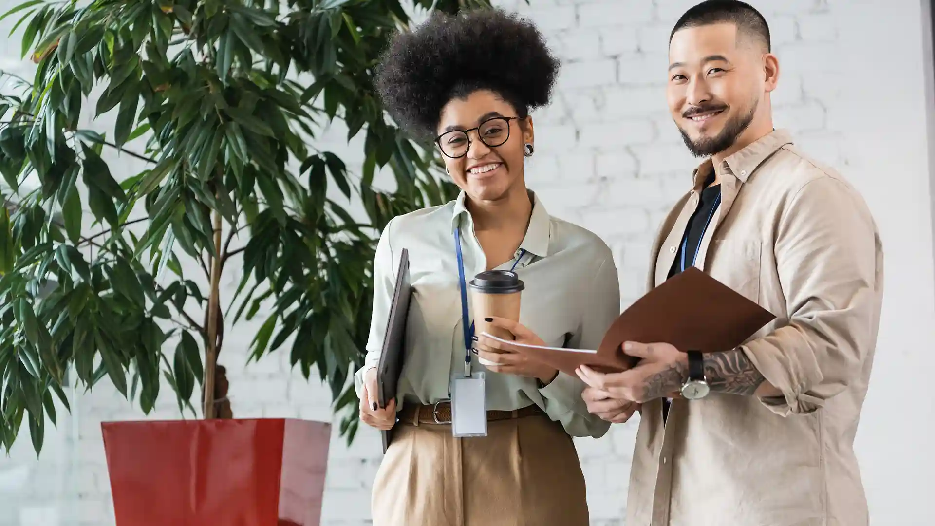 Two professionals from diverse backgrounds smiling confidently in an office setting, representing equal access to job opportunities in Germany.