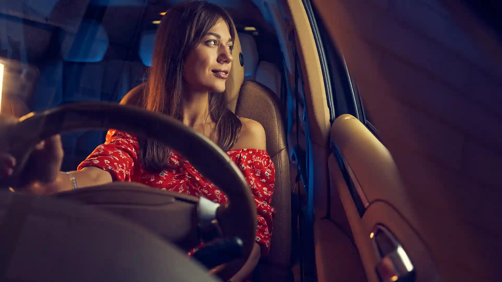 Confident smiling woman sitting in a parked car, representing the peace of mind that comes with having vehicle liability insurance in Germany.